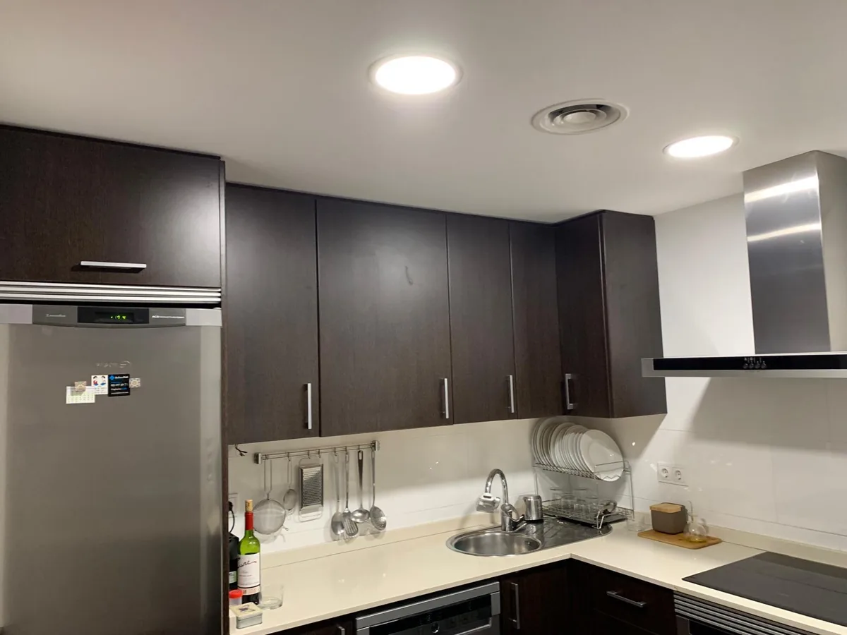 Cocina reformada con muebles oscuros y encimera clara
